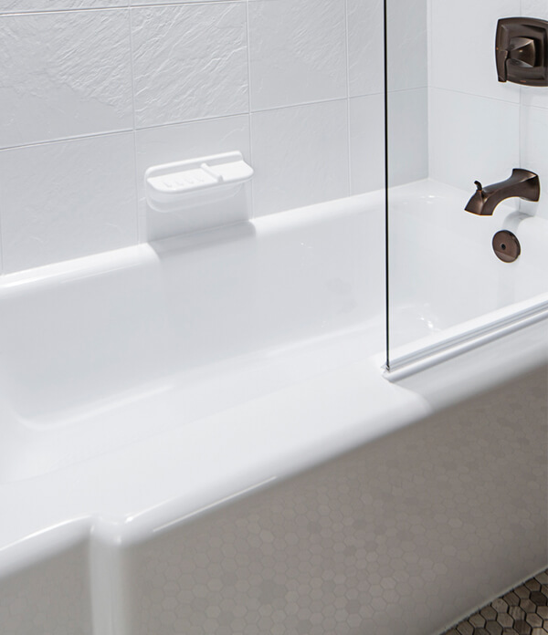 bathtub with glass wall and white tiled wall