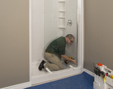 technicien installant la porte en verre de la douche